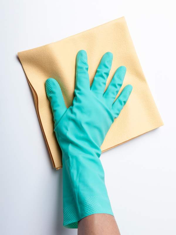 woman from house cleaning company scrubbing wall with gloved hand