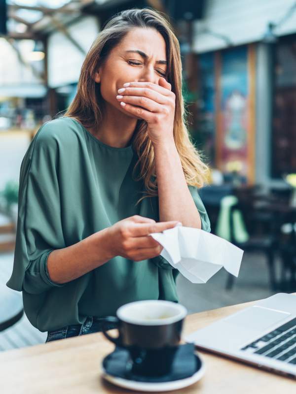 woman sneezing while at office desk