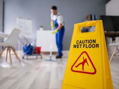 office cleaning company mopping floor with wet floor sign