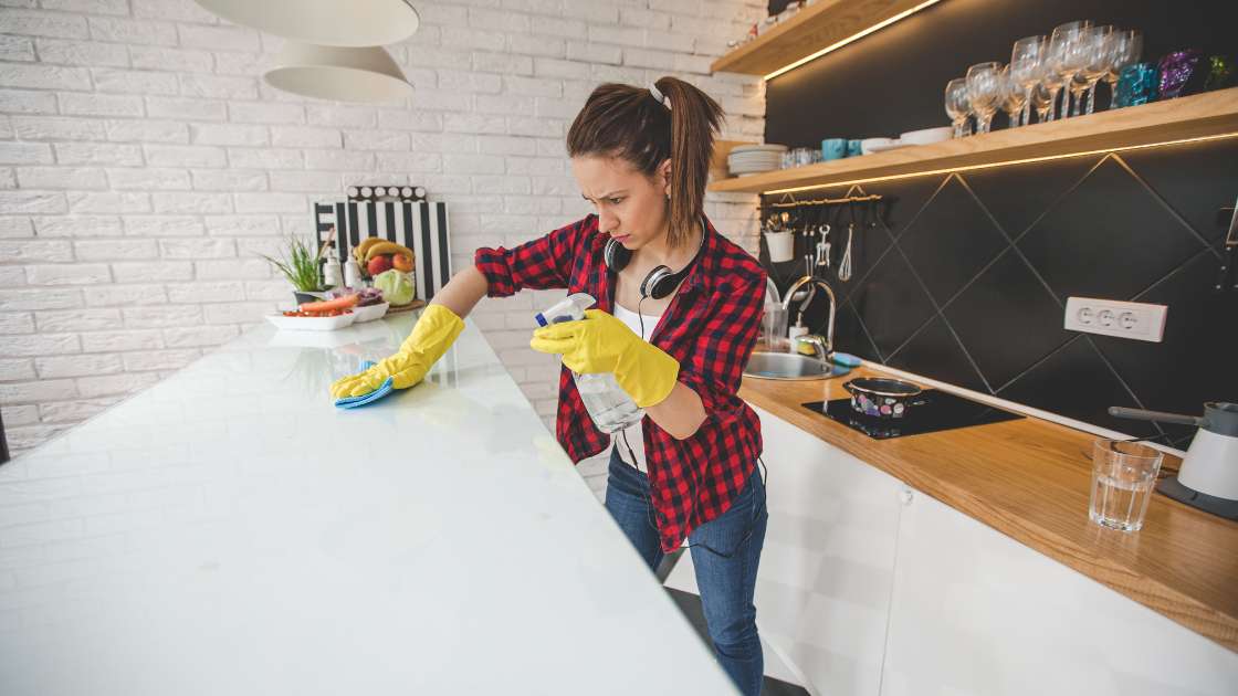 woman in kitchen using house cleaning tips to scrub countertops